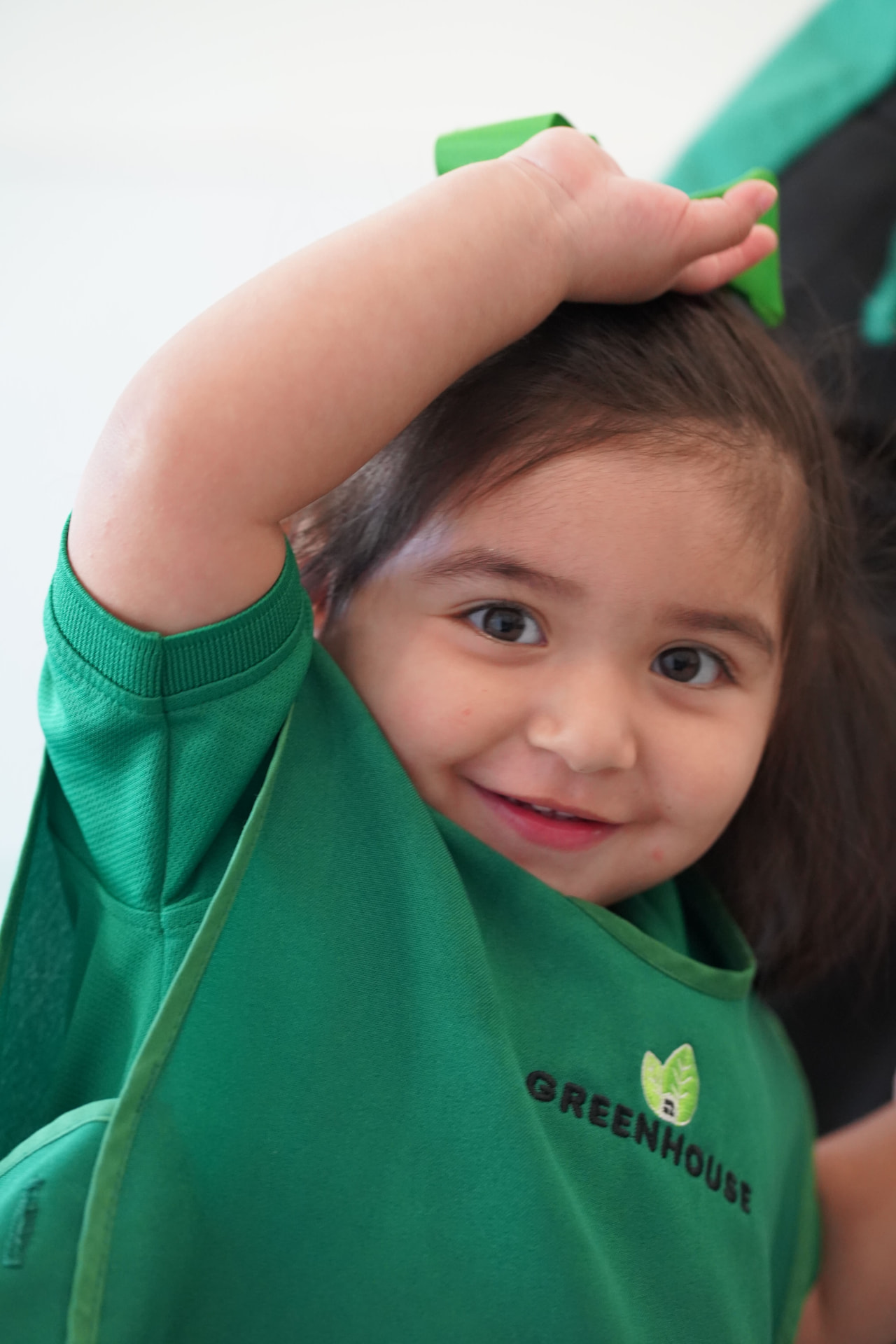 Niña sonriendo con el mandil verde de Greenhouse